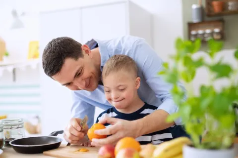 Father and son with Down syndrome peeling an orange