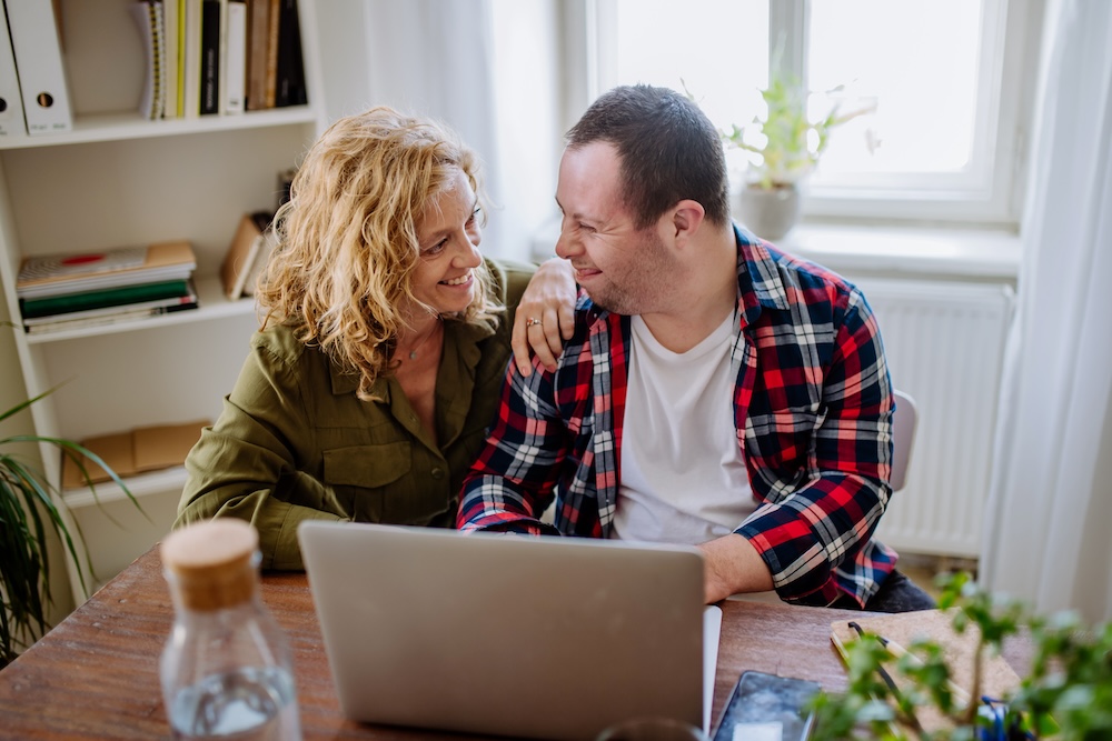 Man with Down syndrome sitting with a woman at a computer