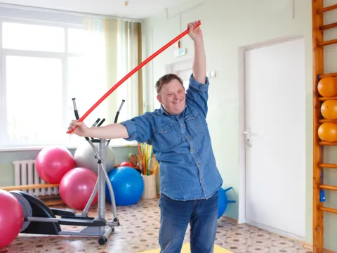 an individual with down syndrome is exercising and smiling