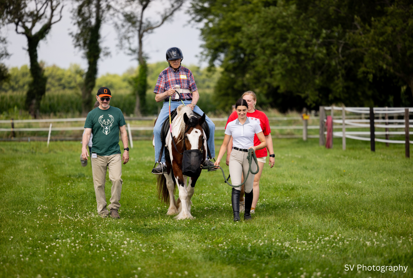 Man riding a horse with two other people walking alongside
