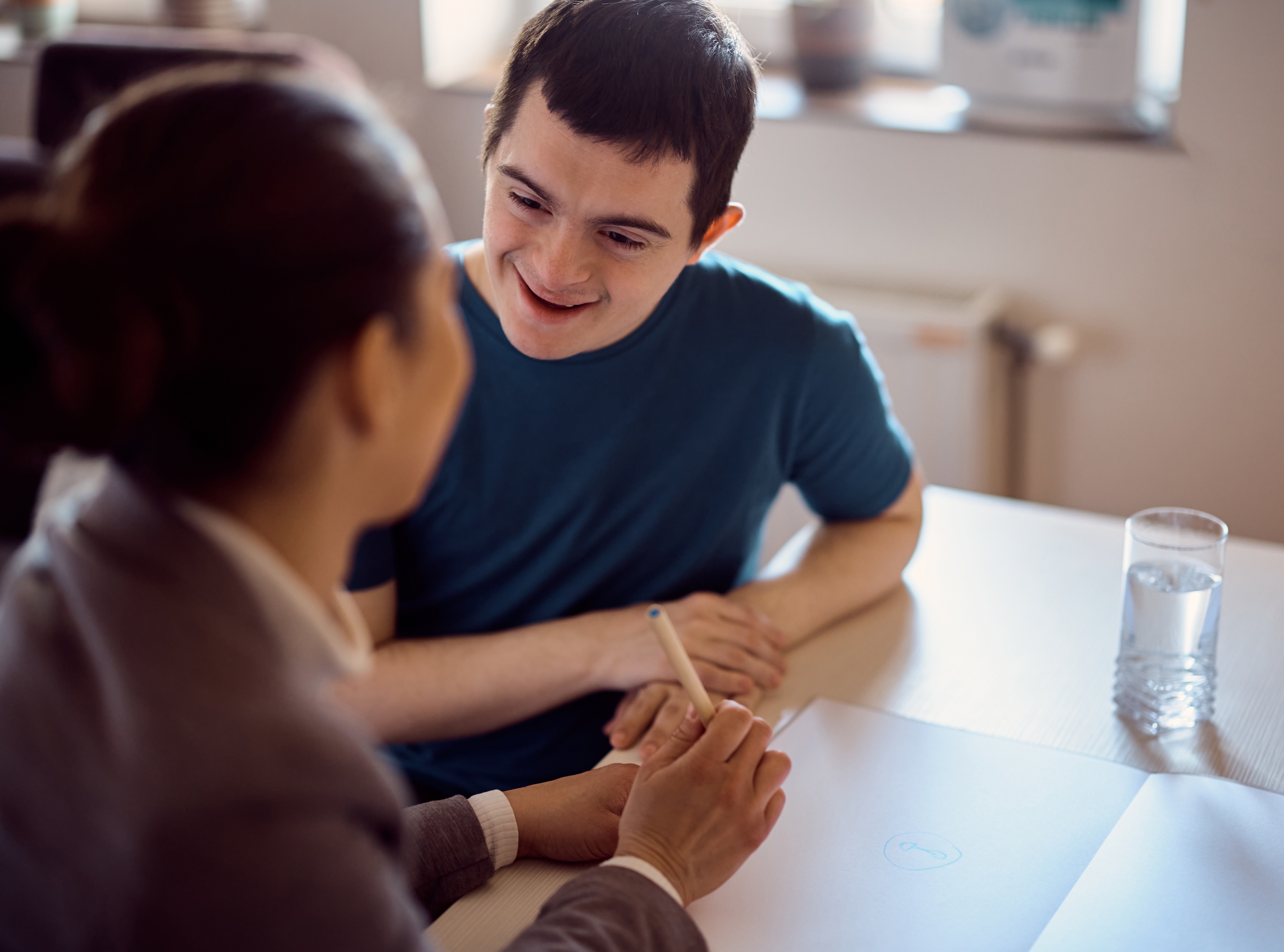 Man with Down syndrome talking with a researcher at a table