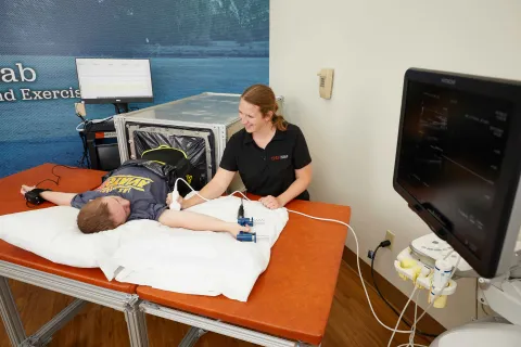 an individual with Down syndrome is laying on a medical table receiving an ultrasound on their arm by a medical professional 