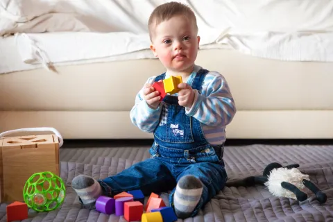 Infant with Down syndrome playing with blocks