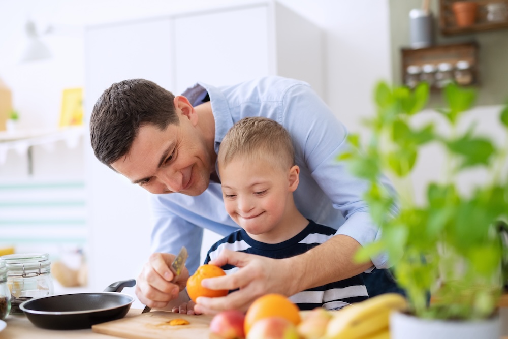Father and son with Down syndrome peeling an orange