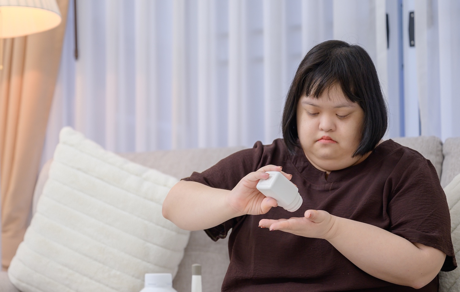 Woman with Down syndrome opening a pill bottle