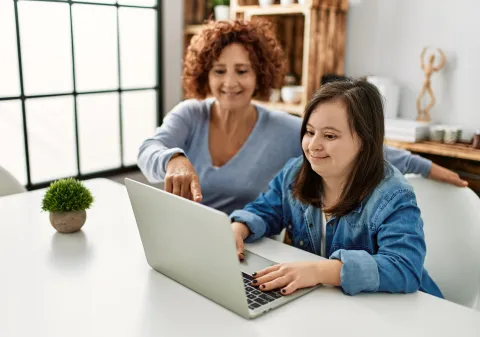 Woman with Down syndrome and her parent looking at a laptop