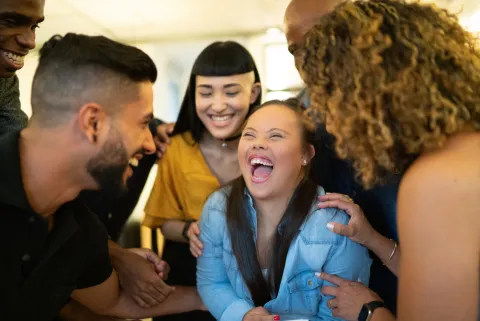Young woman with Down syndrome laughing with a group of friends