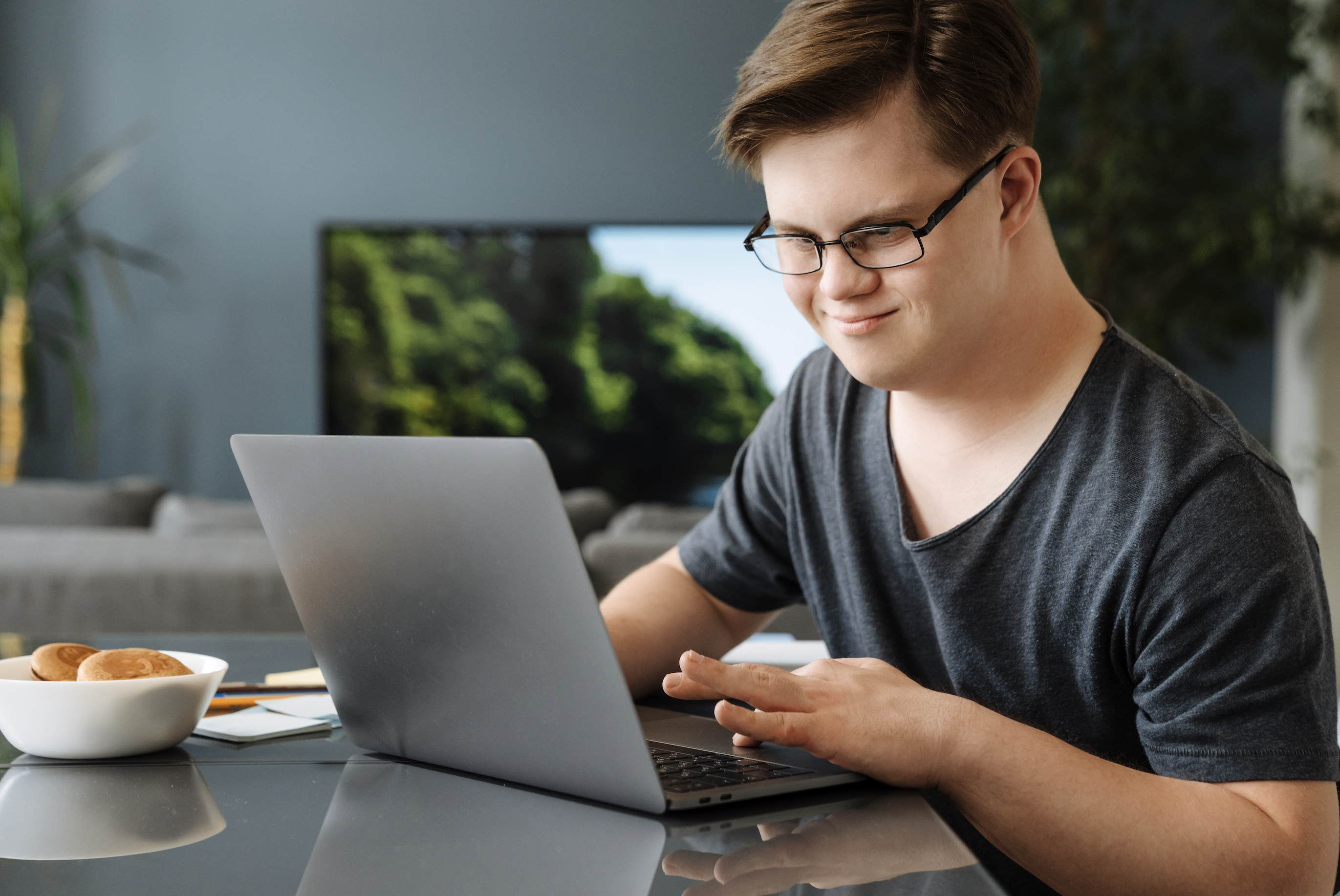 an individual with Down Syndrome is on the computer and smiling
