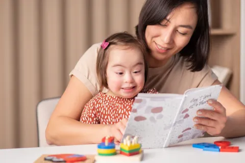 Girl with Down syndrome reading with her mom