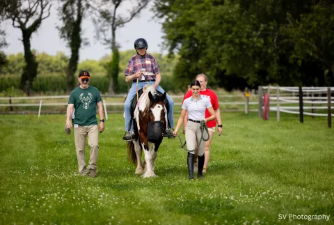 Man riding a horse with two other people walking alongside