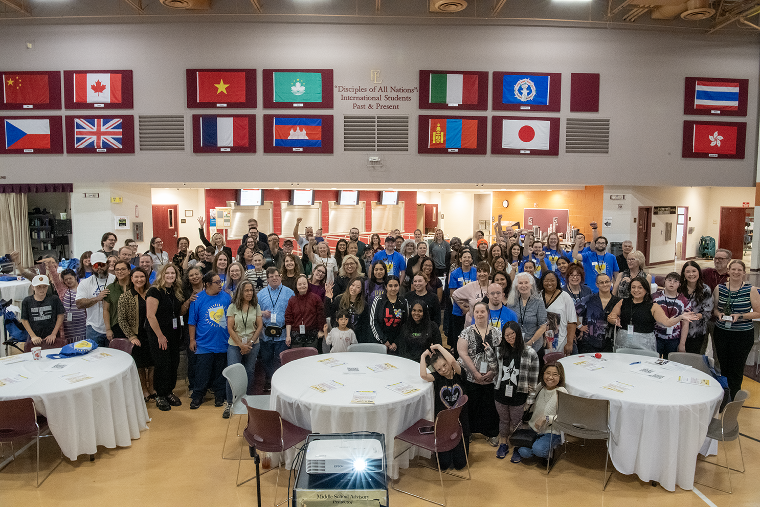 A large group of individuals with and without Down syndrome pose for a picture in a conference room 