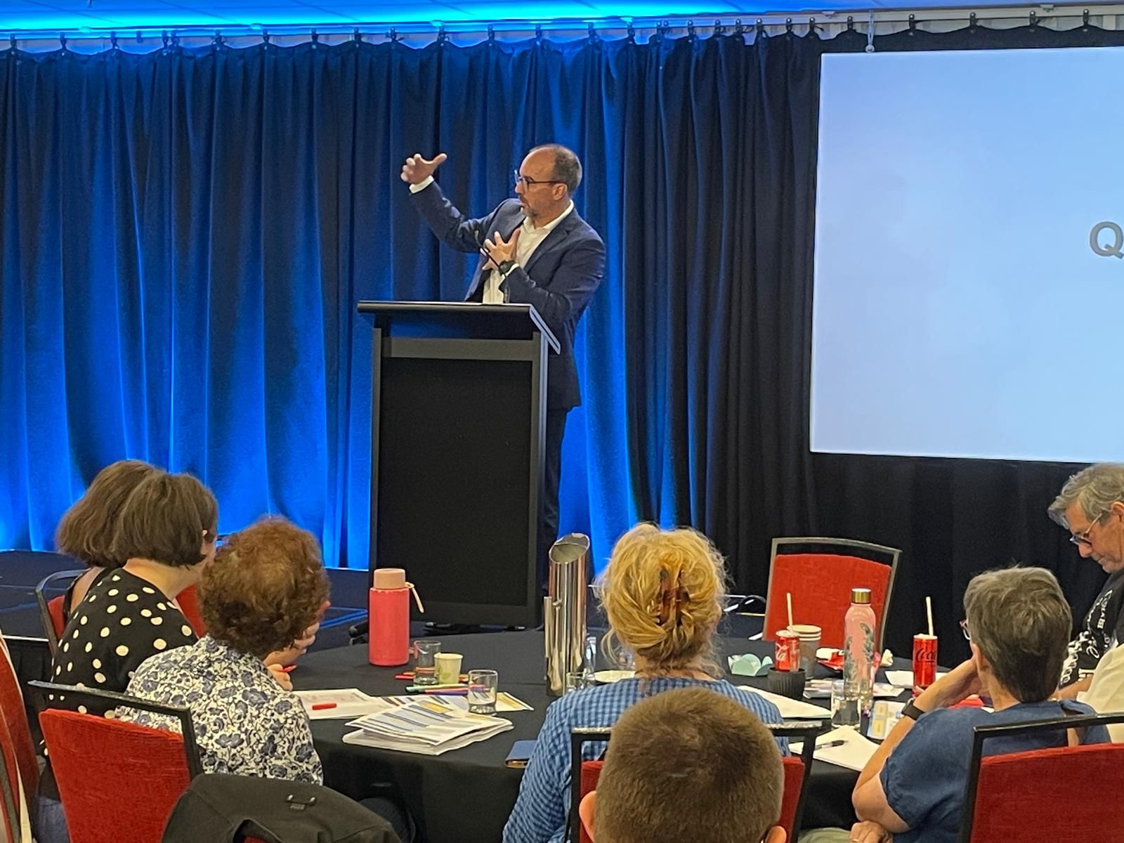 Dr. Espinosa presenting at a podium in front of a large crowd