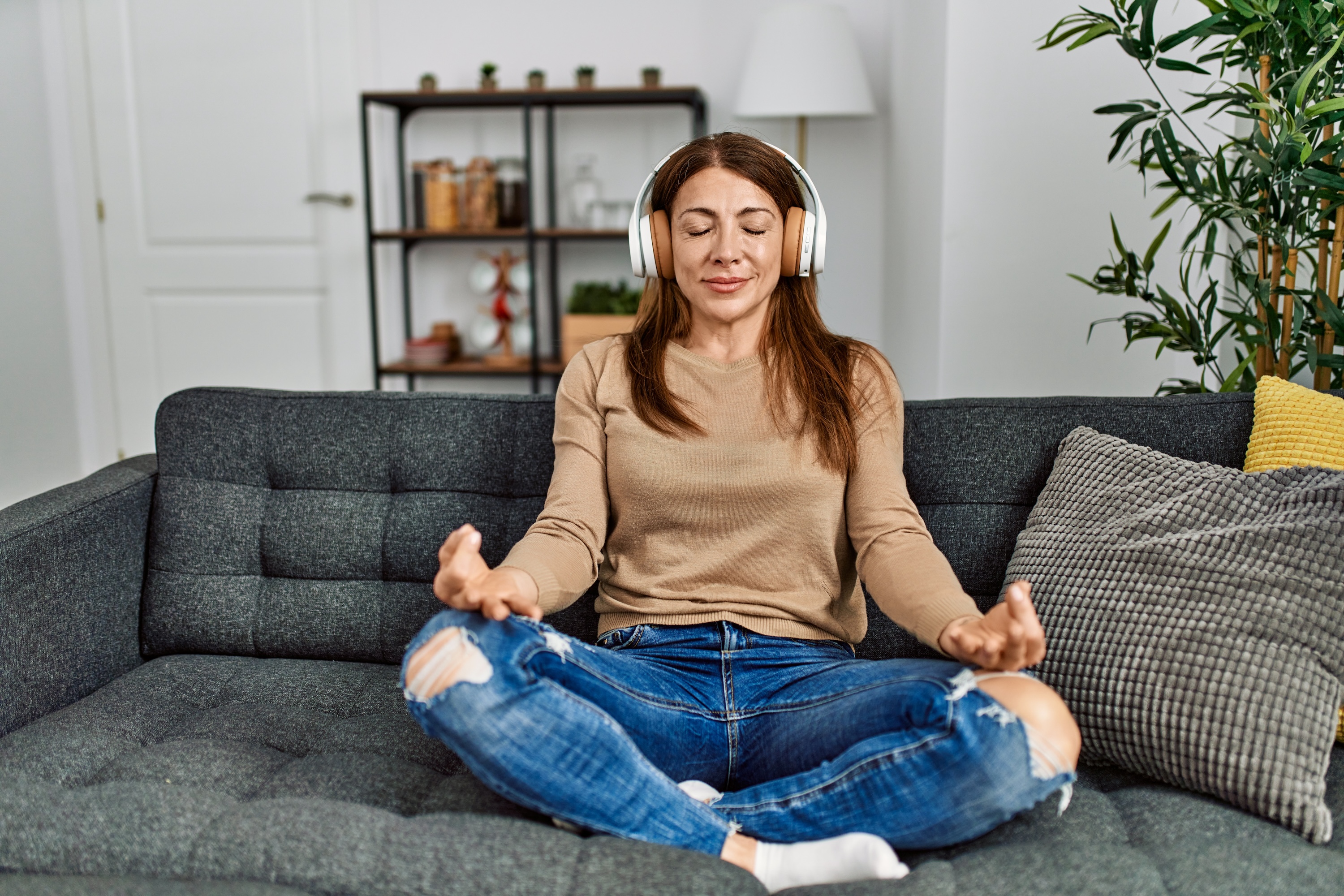 Woman sitting on a couch and meditating with headphones on