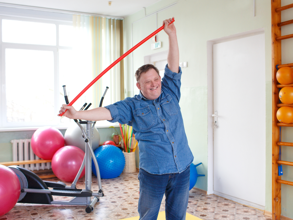 an individual with down syndrome is exercising and smiling