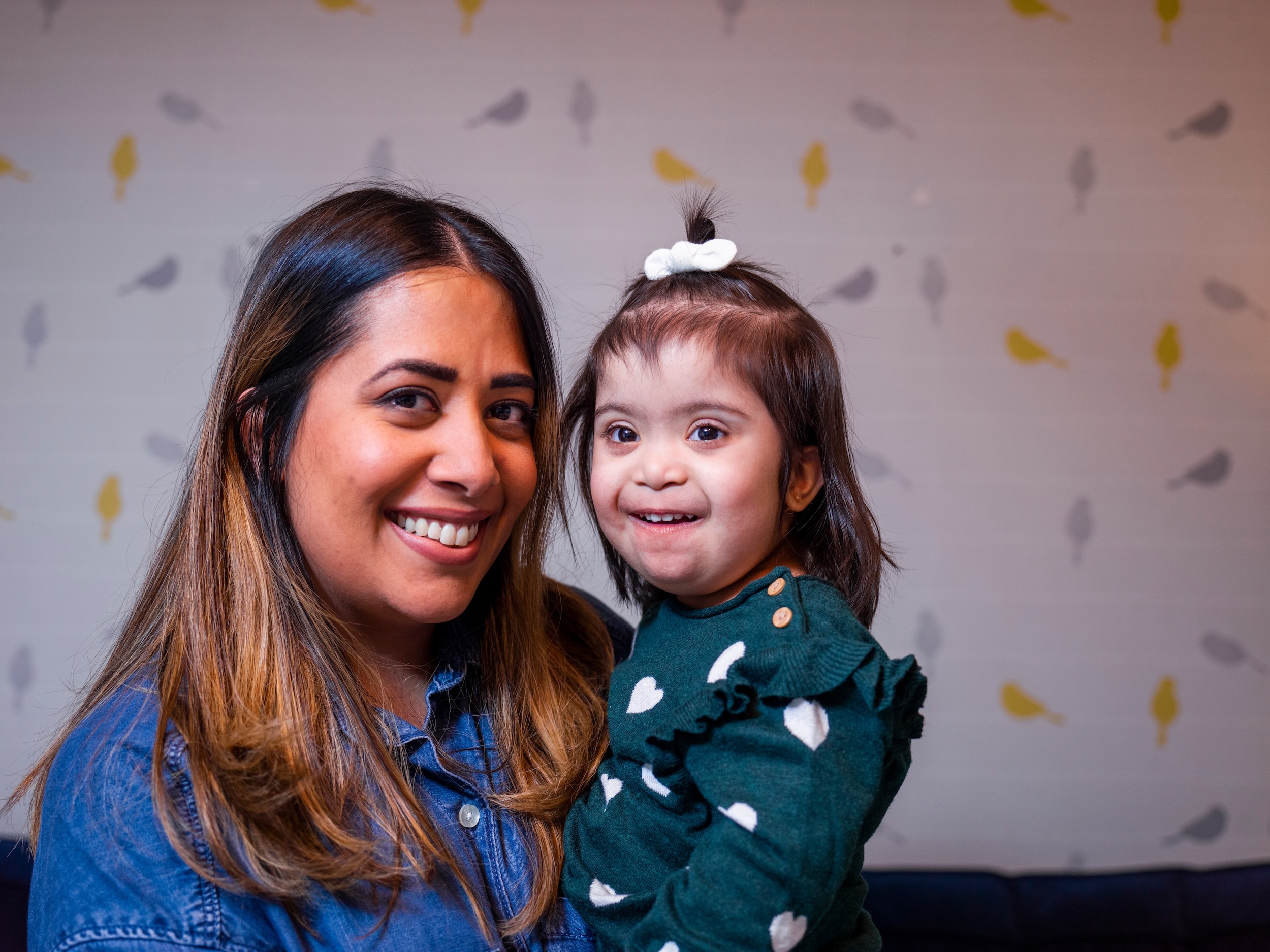 Madre sosteniendo a su joven hija sonriente con síndrome de Down