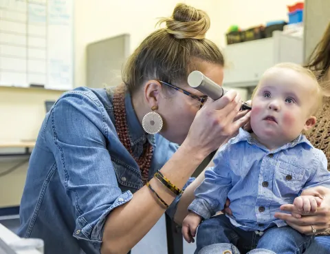 Researcher checking the ears of a child with Down syndrome with and otoscope