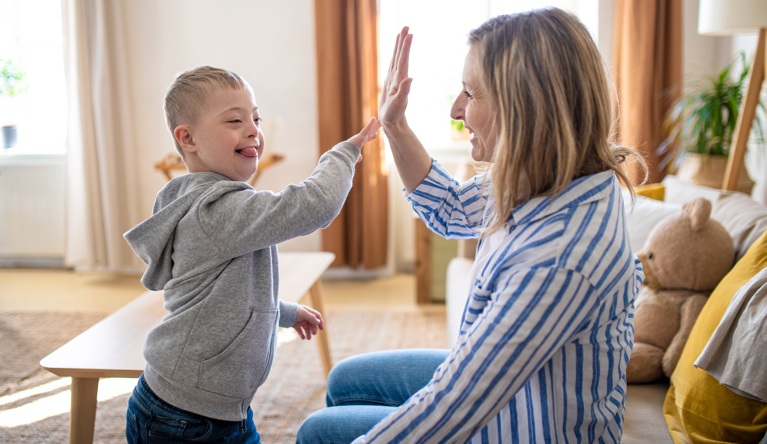 Young boy with Down syndrome high-fiving a woman