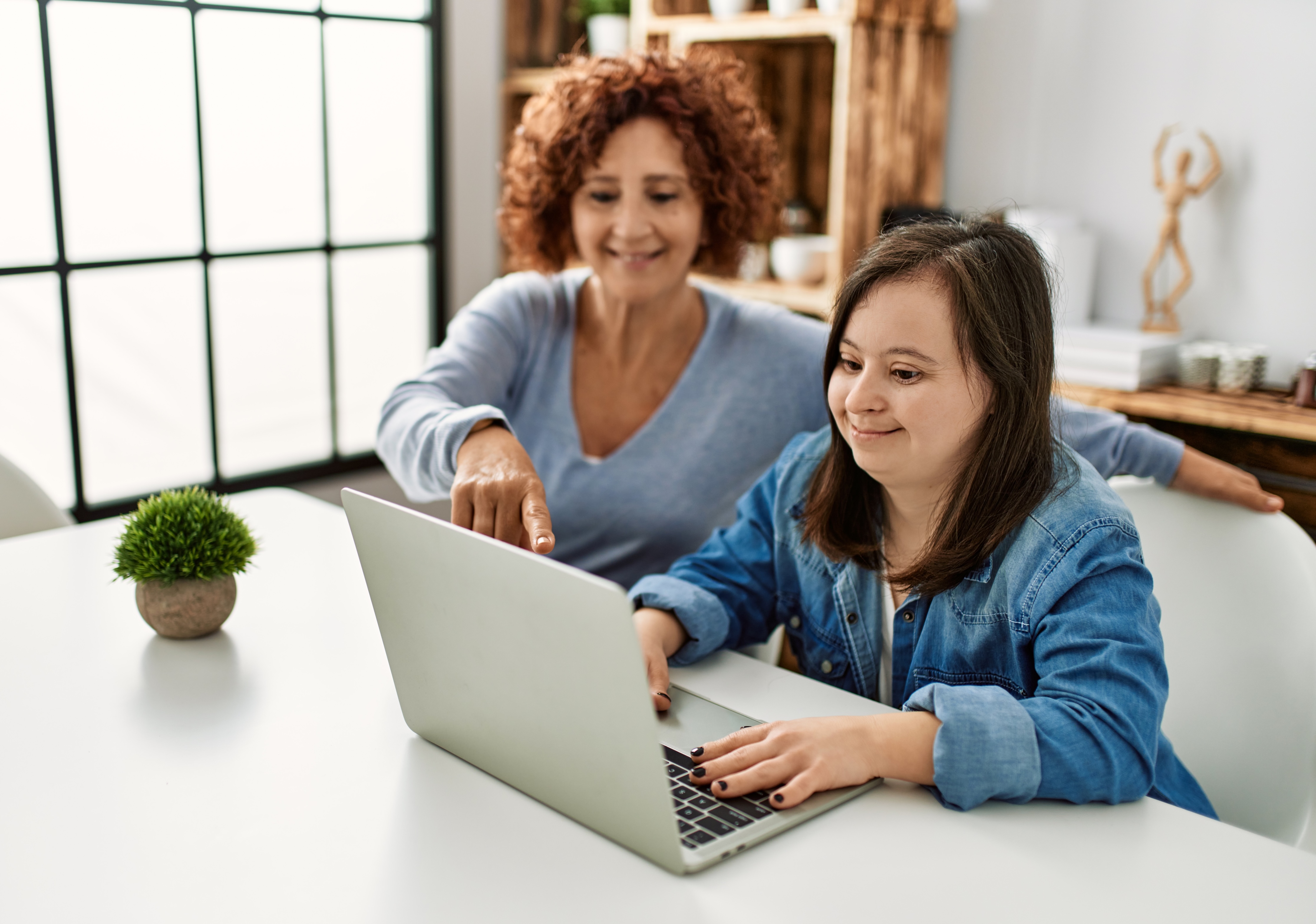 Woman with Down syndrome and her parent looking at a laptop