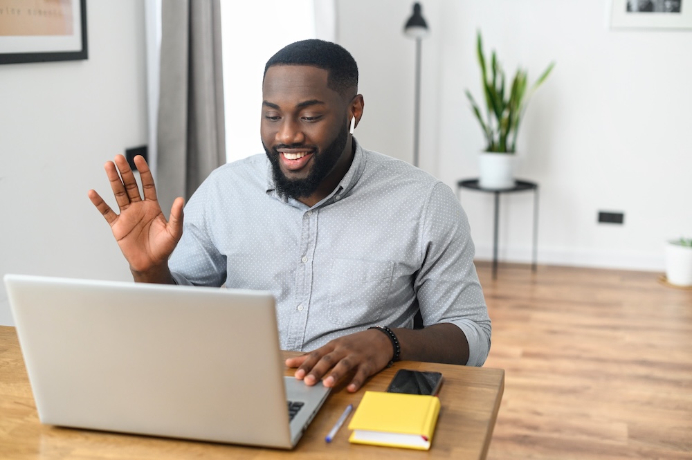 Man on a virtual meeting waving at the computer